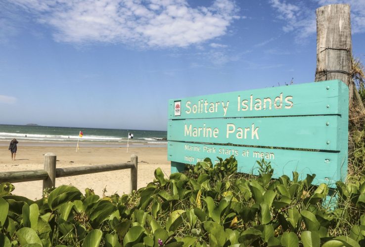 Solitary Islands Marine Park sign at beach with surf safety flags